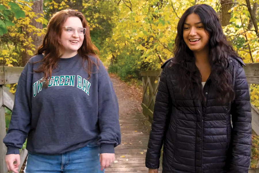Two students walking across a wooden bridge.