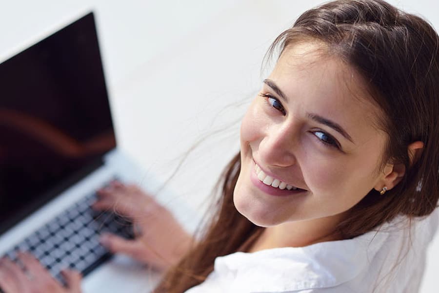 student looking up from her laptop and smiling