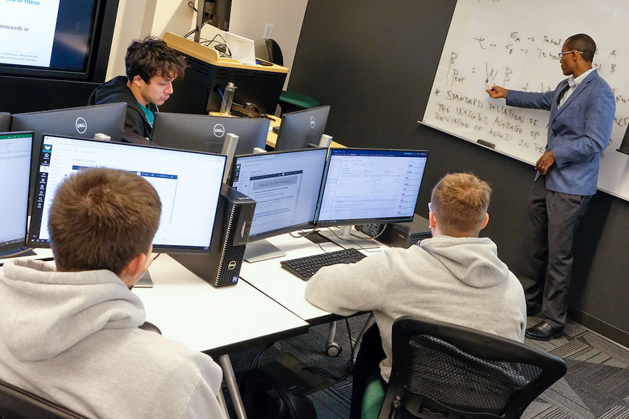 Professor at whiteboard with students in computer lab