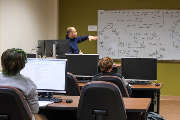 Professor explaining chemical make up on white board