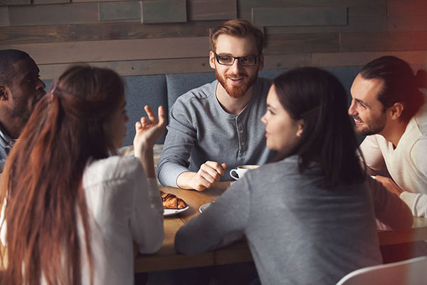 two women and three men talking at a table