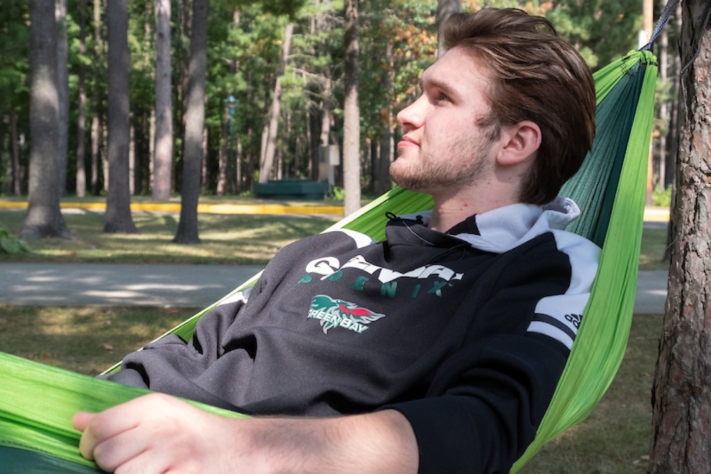 A male student relaxes in a hammock on the Marinette campus.